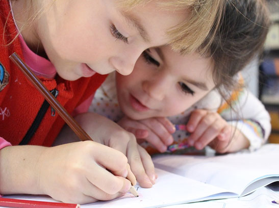 Two girls in school writing in a notebook