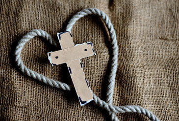 Christian cross in the center of a heart made out of rope.